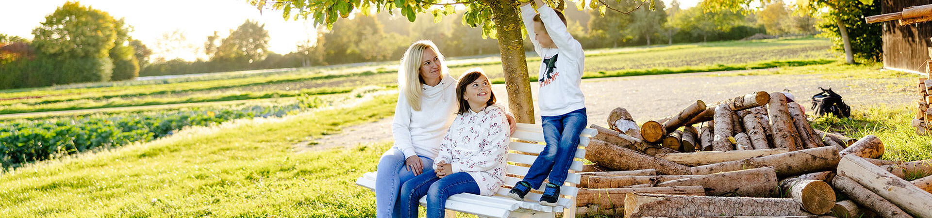 Mary-Ann Schröder mit Kindern unter einem Apfelbaum neben einem Holzstoß